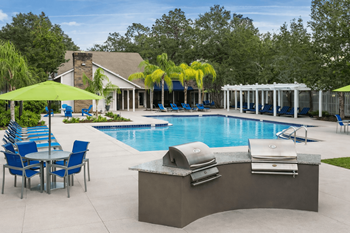 A pool with a table and chairs and a sun shade.